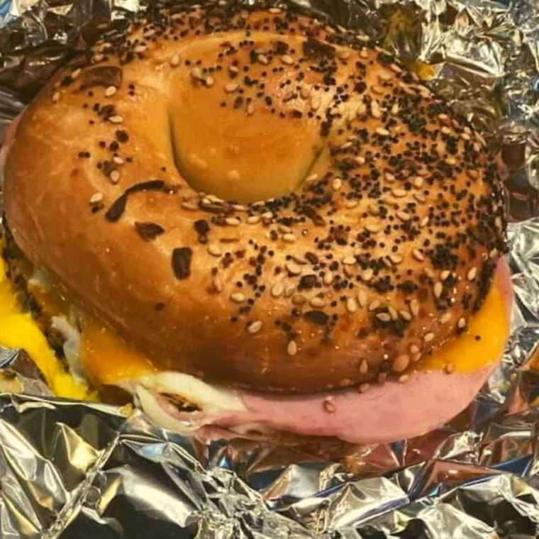 Air Fryer Bagel Sandwich with melted cheese, egg, and crispy bacon on a toasted bagel, served on a plate.