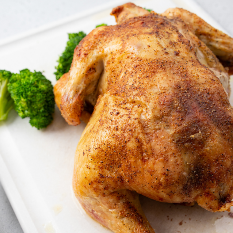 Whole air fryer Cornish hen with crispy golden skin on a white cutting board