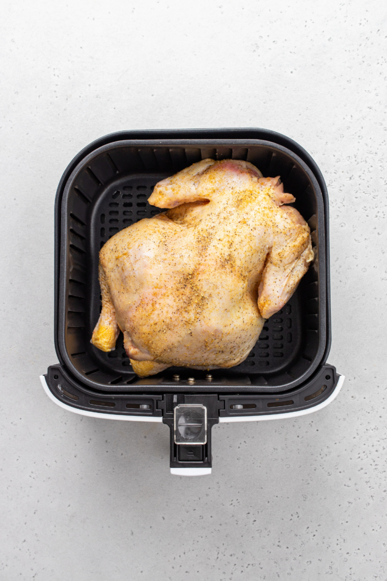 Seasoned Cornish hens placed in the air fryer basket to cook