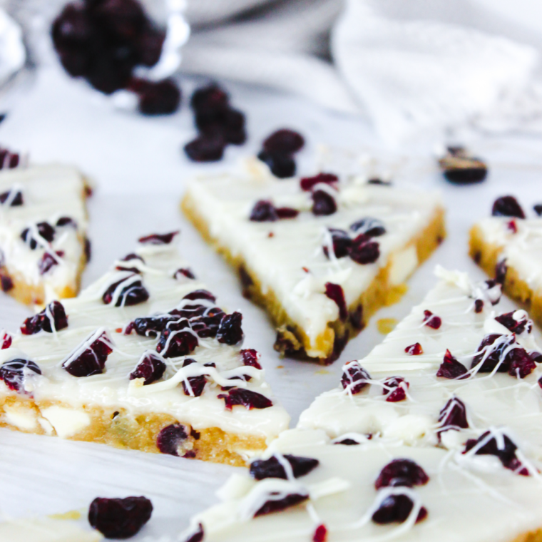 Close up of a single cranberry bliss bar triangle showing the chewy white chocolate blondie base
