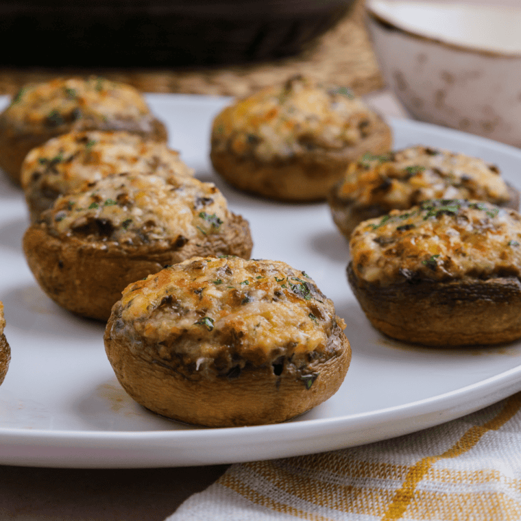 A plate of Carrabba’s Italian Grill Stuffed Mushrooms Parmigiana, topped with marinara sauce and melted Parmesan cheese.