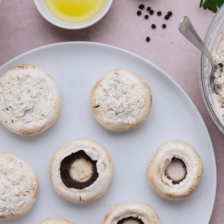 Filling mushroom caps with a savory stuffing mixture, gently pressing to pack it in for even baking.