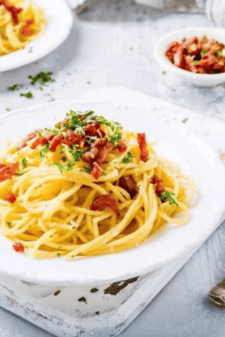 Close-up of creamy carbonara pasta with crispy bacon and black pepper.