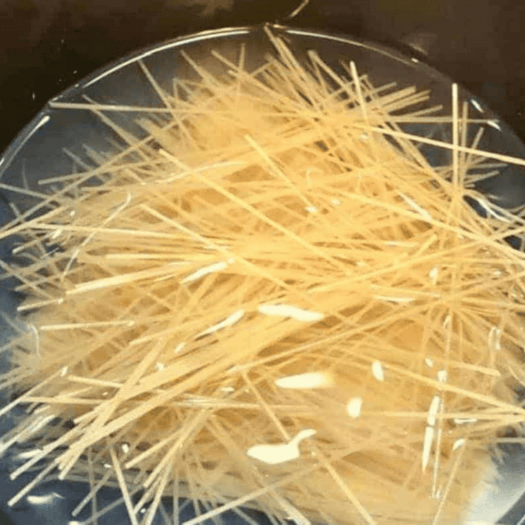 Spaghetti broken in half and arranged in a crisscross pattern in the Instant Pot with water