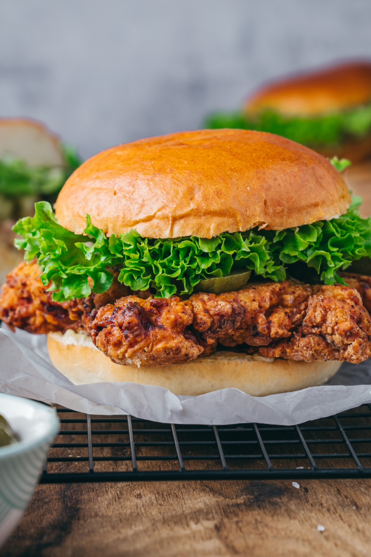 Copycat Ina Garten fried chicken sandwich with herb mayo, lettuce, and pickles on a toasted potato bun