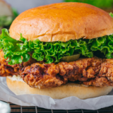 Ina Garten fried chicken sandwich with buttermilk herb mayo, lettuce, and pickles on a toasted potato bun