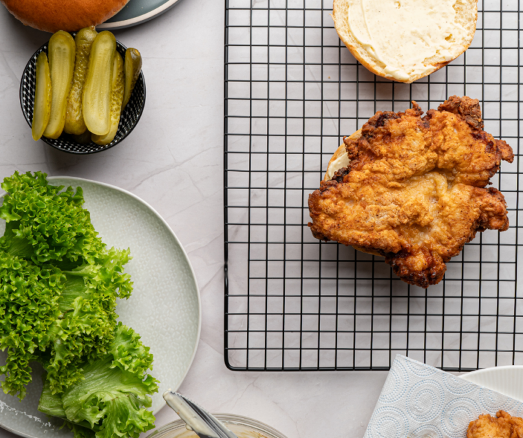 Two breaded chicken cutlets frying in oil in a Dutch oven until deep golden