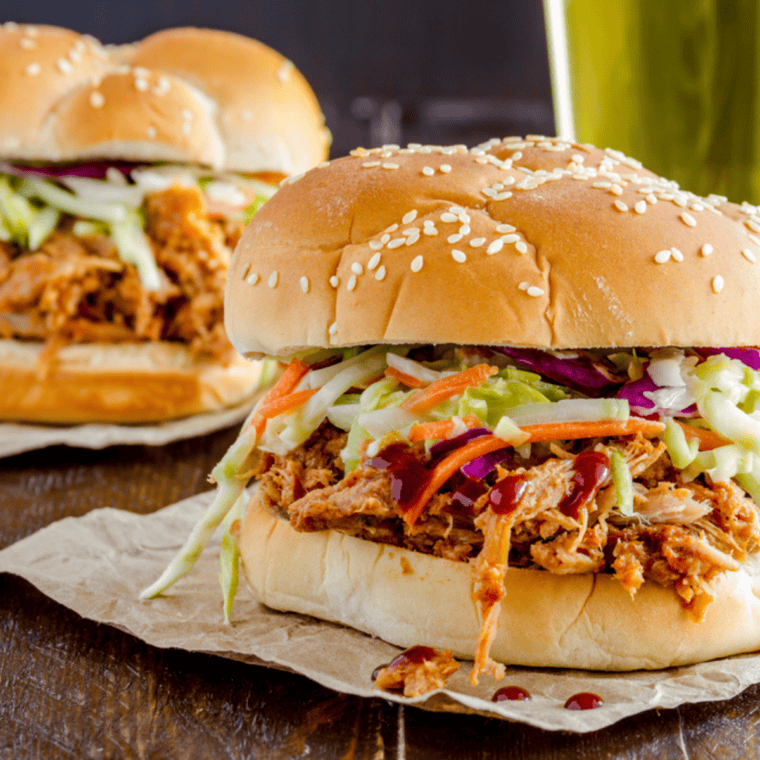 A BBQ pulled pork sandwich on a toasted brioche bun topped with coleslaw, made in the Instant Pot.