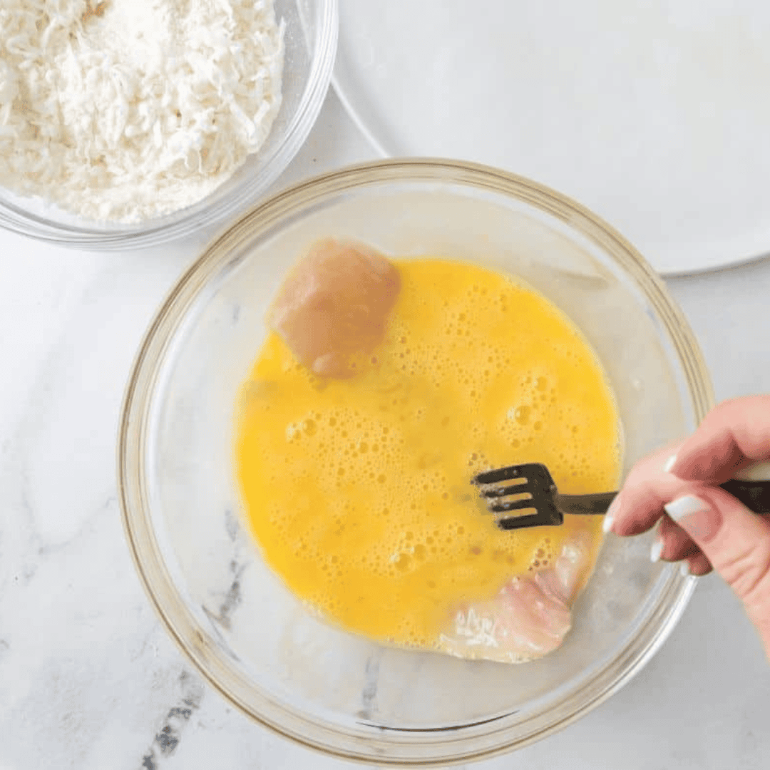 Mixing unsweetened flaked coconut, coconut flour, and sea salt in one bowl, and beating eggs in a separate small bowl for coconut crusted tilapia preparation