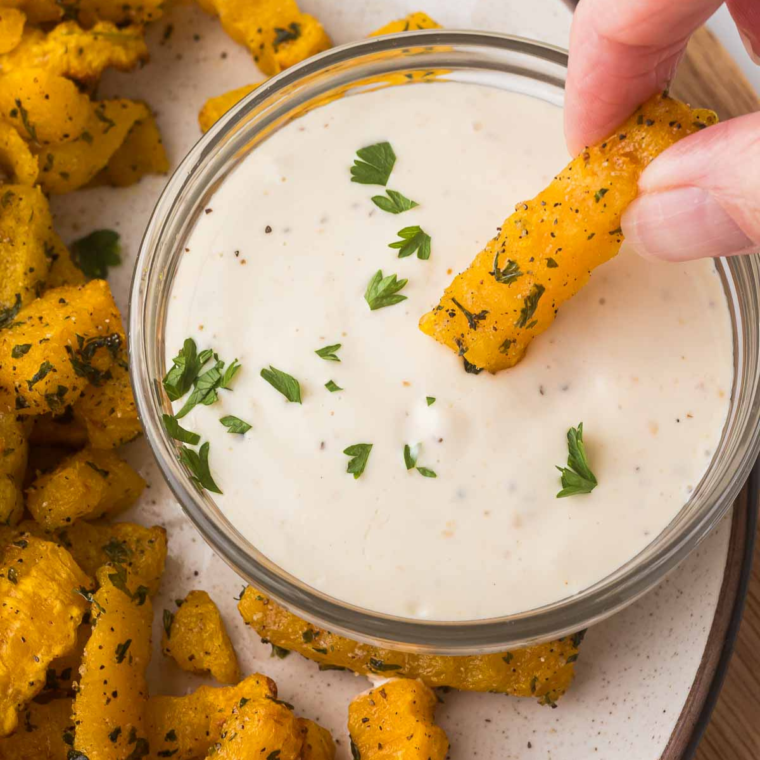 Air Fryer Butternut Squash Fries being dipped in ranch dressing for a crispy and creamy snack.