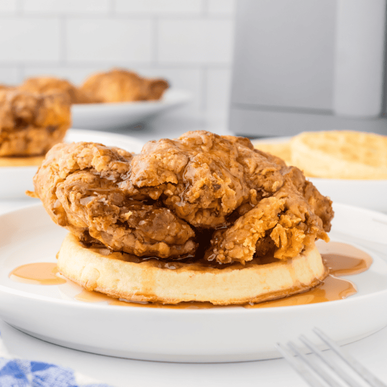 Crispy Air Fryer Chicken and Waffles on a Plate - A plate featuring golden-brown air fryer chicken served on top of fluffy waffles with syrup drizzled on top.