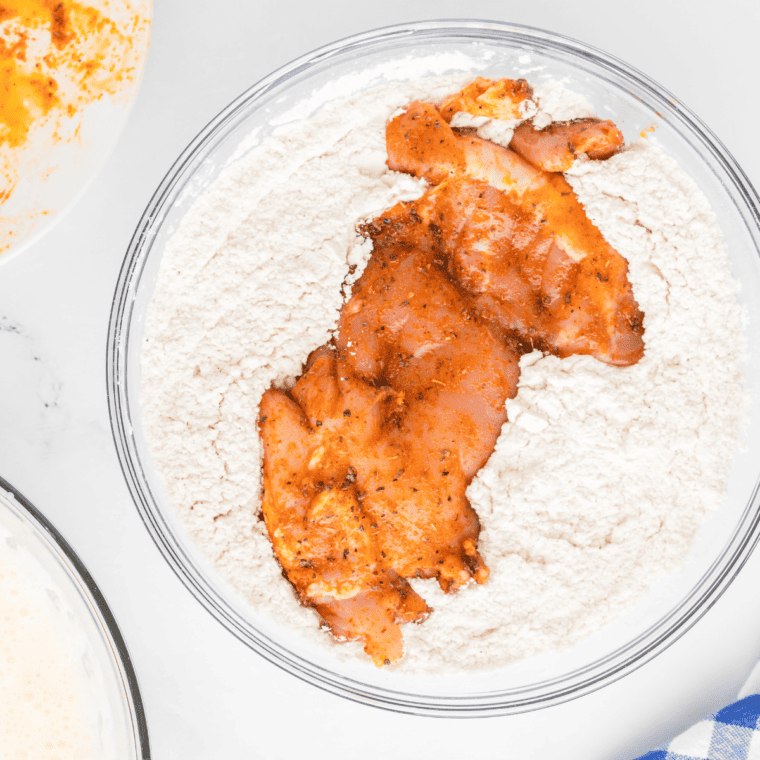 Coating the chicken pieces with the seasoned flour mixture.