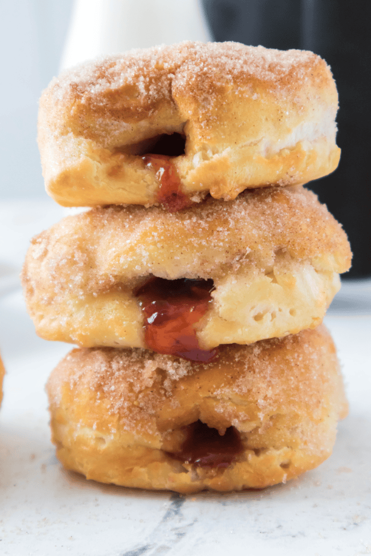Air fryer jelly donuts filled with strawberry jam on a white plate