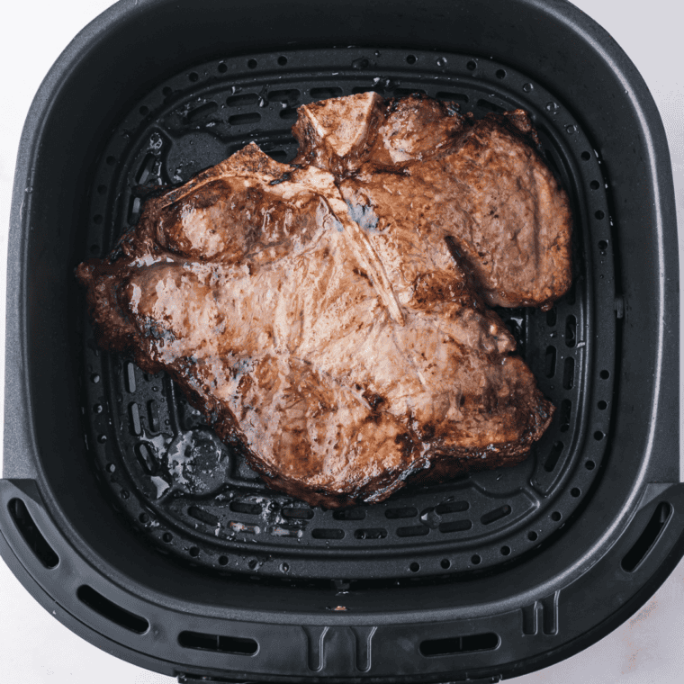 Instant-read thermometer in the thickest part of an air fryer porterhouse steak reading 130°F