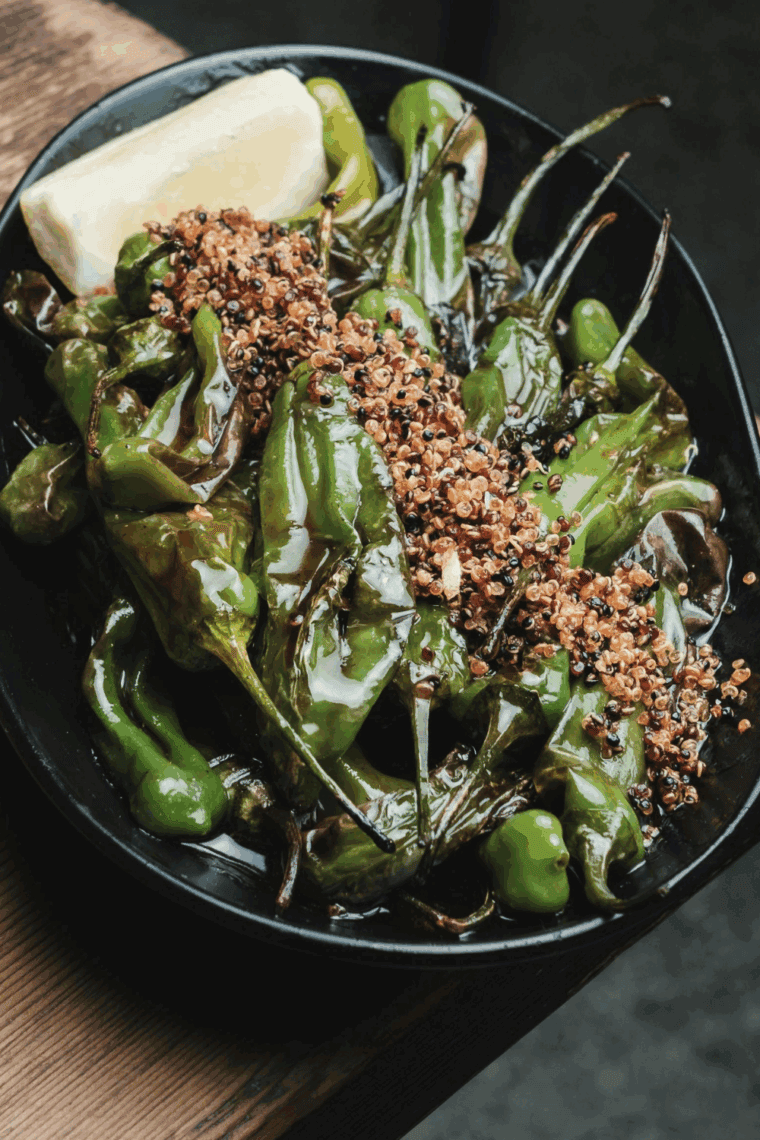 Blistered Benihana-style shishito peppers served hot on a plate with dipping sauce.