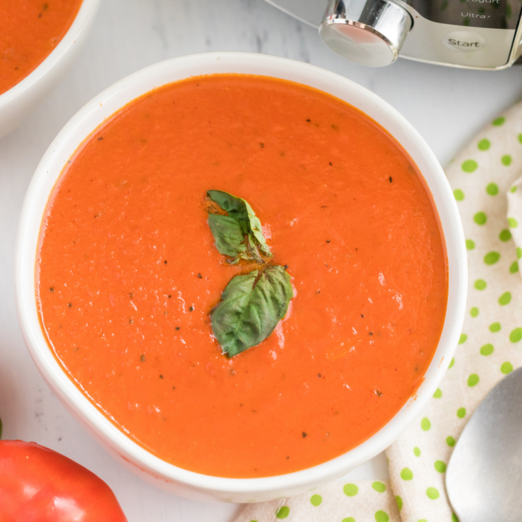 Finished slow cooker Nordstrom tomato basil soup in a white bowl with a grilled cheese sandwich