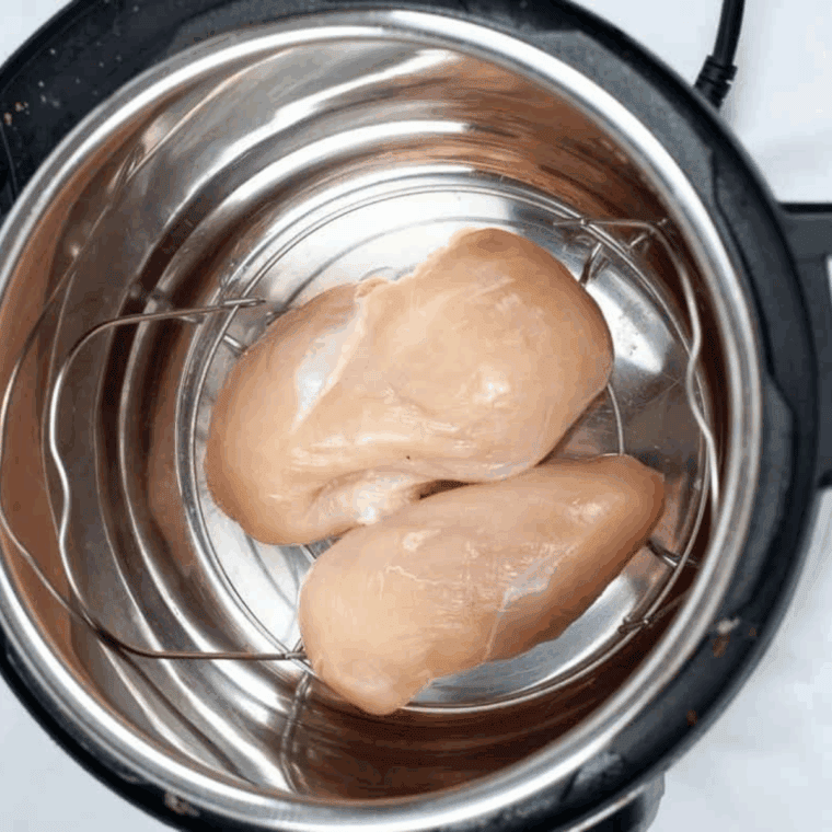 Add chicken breasts, butter, buffalo sauce, honey, cider vinegar, and Tabasco to the Instant Pot, coating chicken evenly.