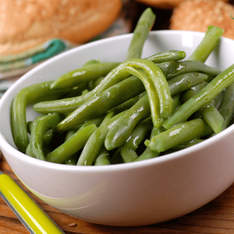 Steamed green beans cooked in the Instant Pot, served tender and lightly seasoned on a white plate.