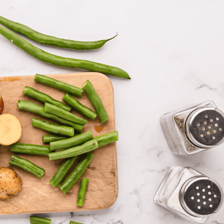 Fresh green beans being washed and trimmed on a cutting board.