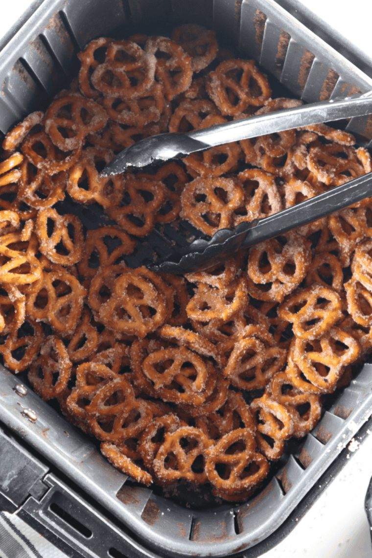Soft pretzel with coarse salt cooking in an air fryer basket