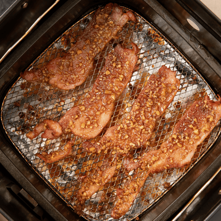 Strips of bacon laid flat in a single layer in an air fryer basket