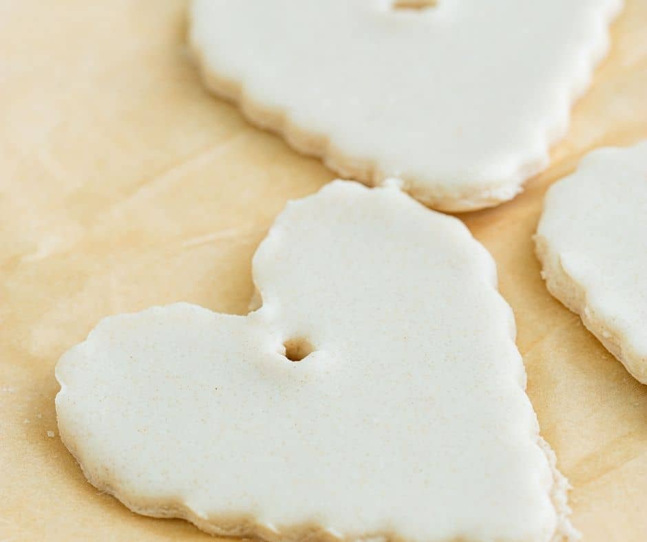 Cutting dough into ornament shapes with a cookie cutter, creating a hole for hanging, and air frying for 30 minutes until fully dried.