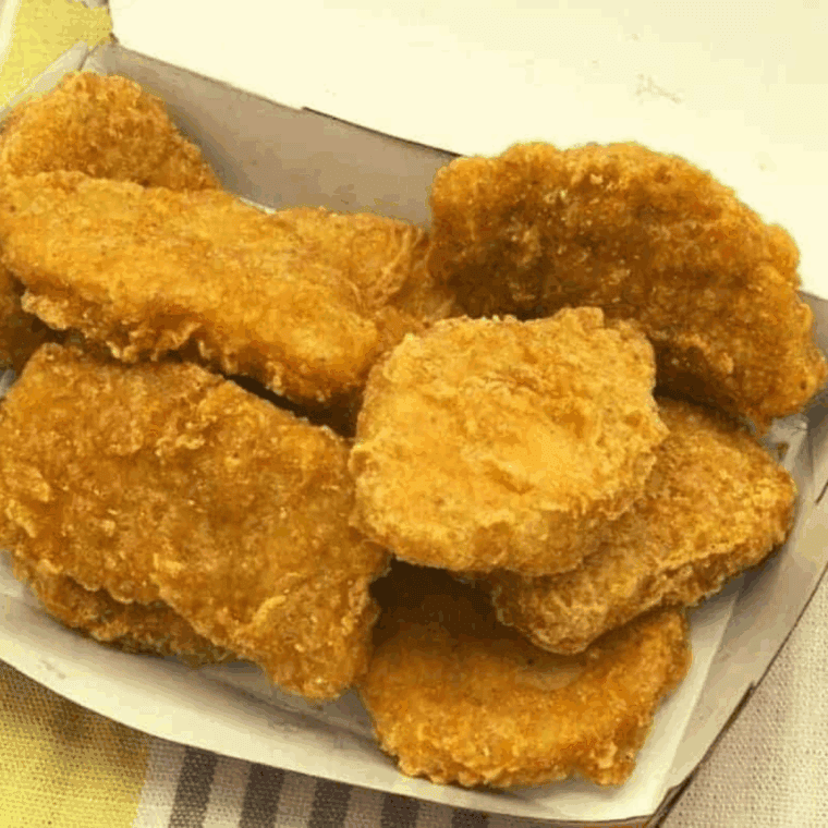 Reheated McDonald’s Chicken McNuggets in an air fryer basket, golden and crispy