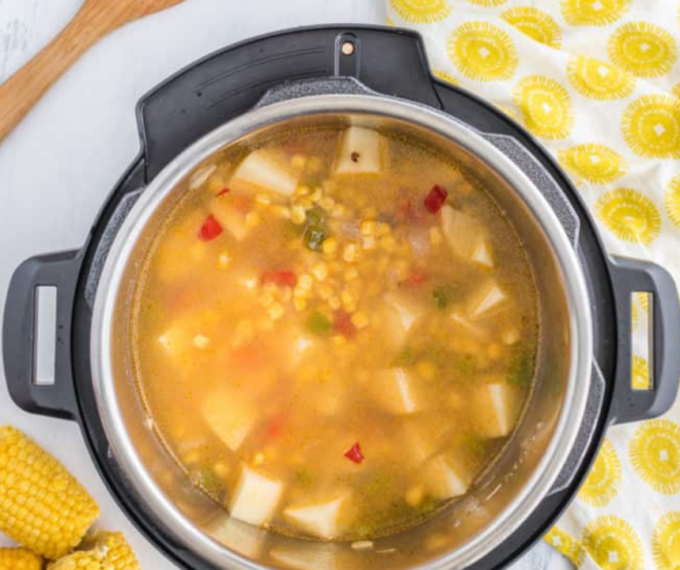"Panera Summer Corn Soup cooking in the Instant Pot, with steam and ingredients visible inside the pot."