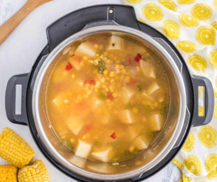 "Finished bowl of Panera Summer Corn Soup with a garnish of fresh herbs and a slice of crusty bread on the side."