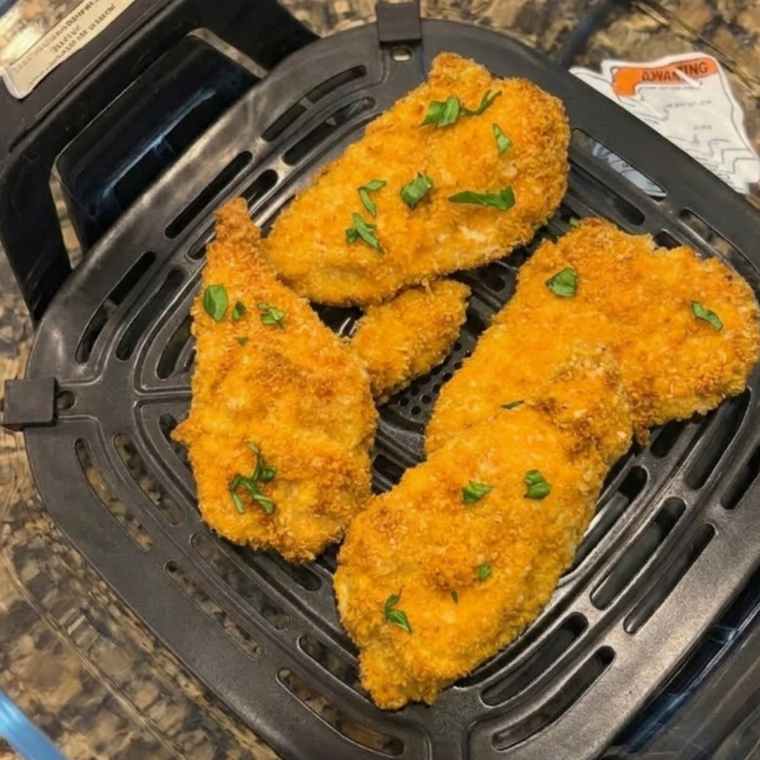 Breaded chicken cutlets crisping inside a Ninja Crispi air fryer.