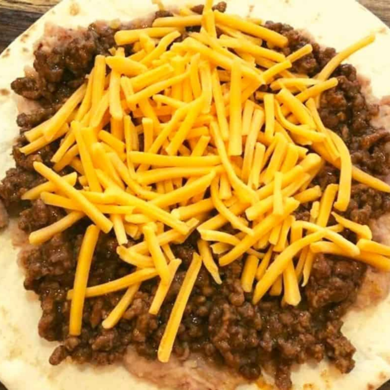 Layering tortillas, refried beans, taco meat, and cheese in a springform pan