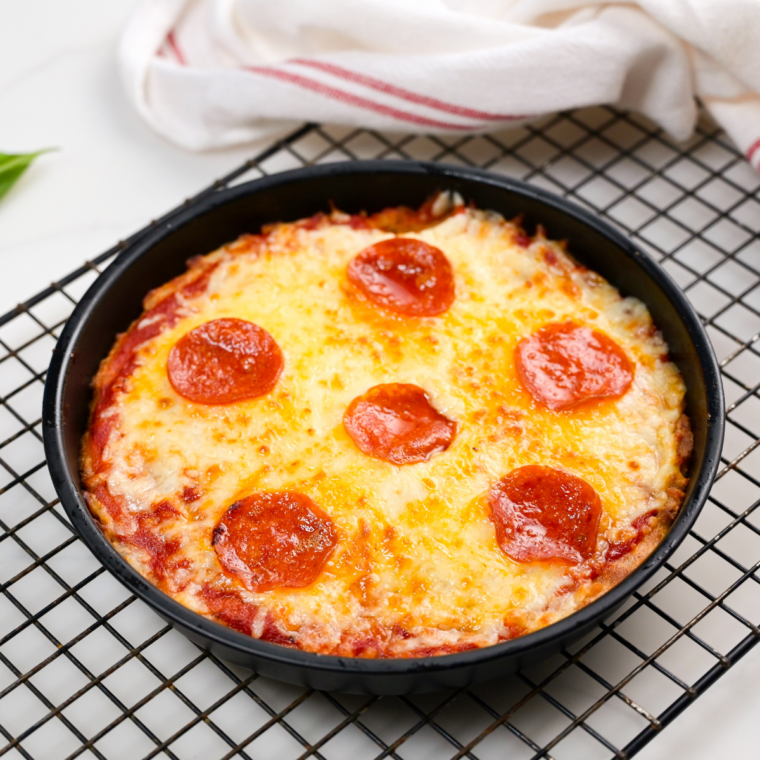 2 Ingredient Air Fryer Pizza with melted mozzarella cooling on a wire rack set in a sheet pan