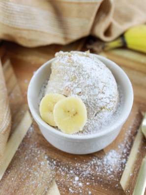 Golden air fryer banana bread mug cake in a white ramekin, topped with a banana slice