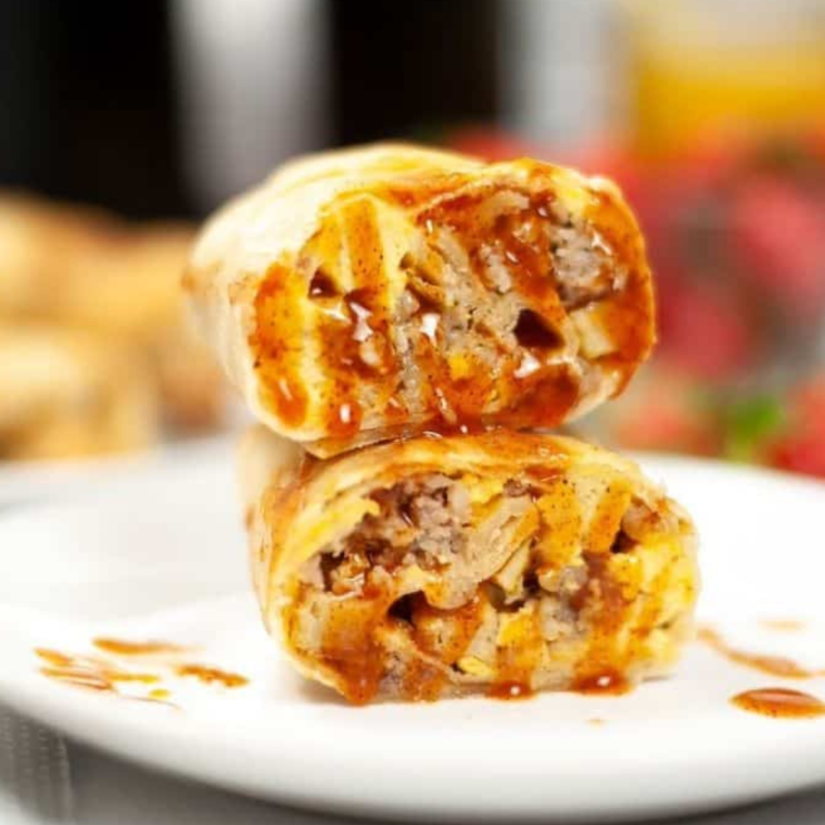Golden, crispy air fryer breakfast chimichangas filled with sausage, eggs, and potatoes on a plate
