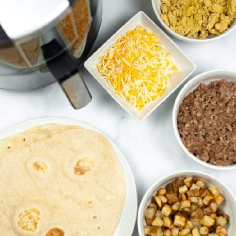 Ingredients for air fryer breakfast chimichangas: flour tortillas, sausage, eggs, potato, and shredded cheese