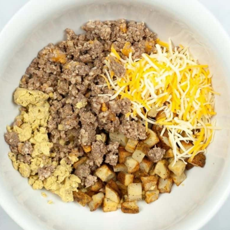 Tortillas, scrambled eggs, crumbled sausage, and diced potatoes laid out for breakfast chimichangas