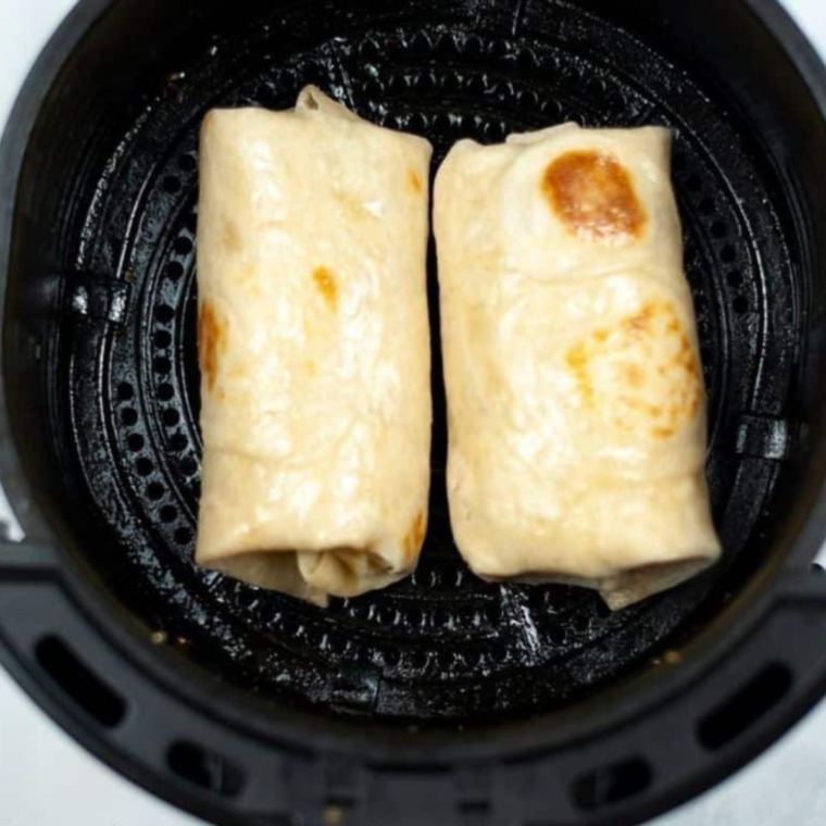 Rolled breakfast chimichangas in a single layer in the air fryer basket before cooking