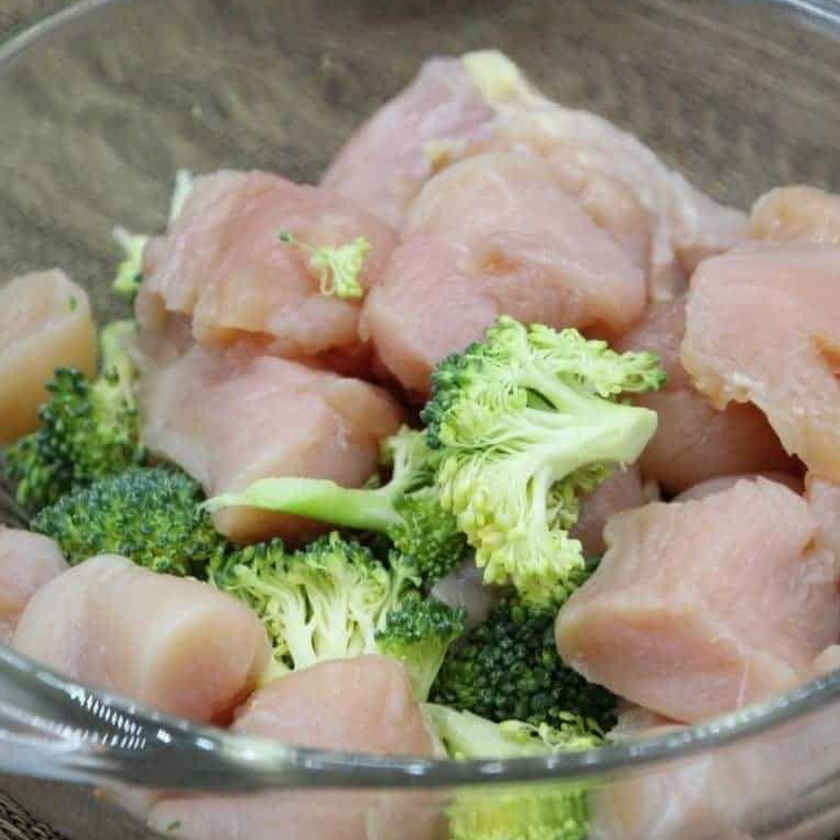 Ingredients needed for chicken and broccoli in a glass bowl.