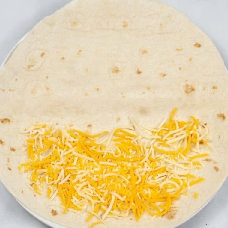 air fryer quesadilla assembly tortilla layered with creamy jalapeño sauce chicken and three cheeses folded in half for melting and sealing filling