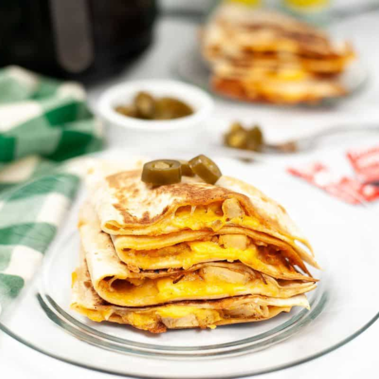 crispy air fryer quesadilla cut into four slices with dipping sauce on the side