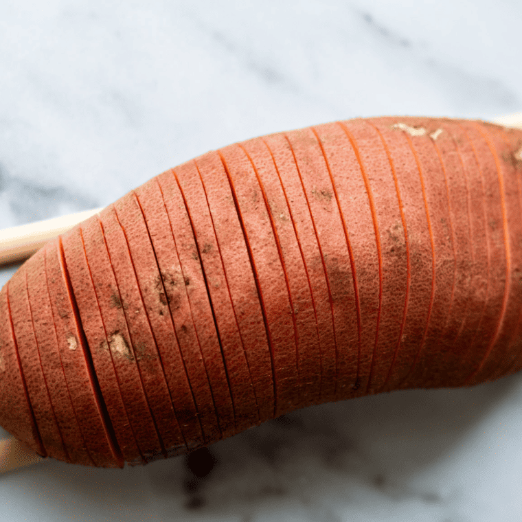  Close-up of slicing sweet potatoes into hasselback cuts for air frying.