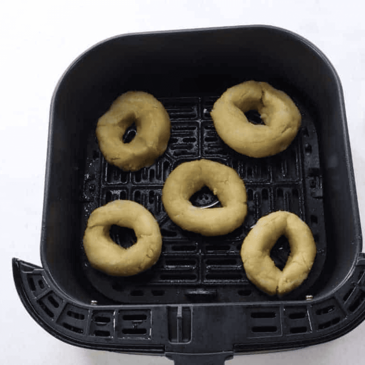 Six equal portions of fathead dough divided on parchment paper, ready to shape into keto bagels.