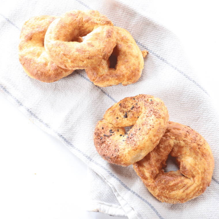 Air fryer keto bagel sliced in half and spread with cream cheese on a marble countertop in morning light.