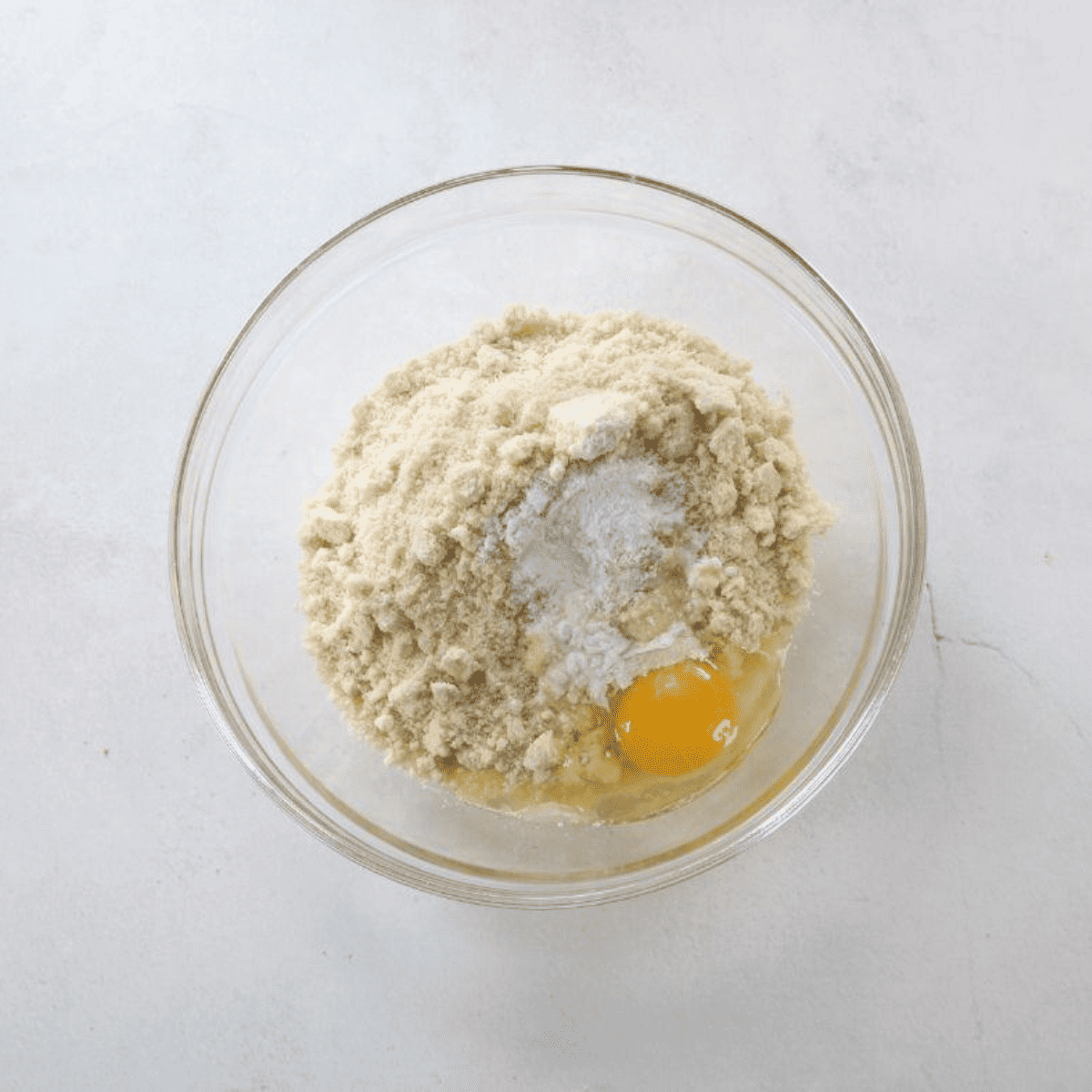 Shredded mozzarella and cream cheese melted together in a clear glass bowl, the first step for air fryer keto bagels.