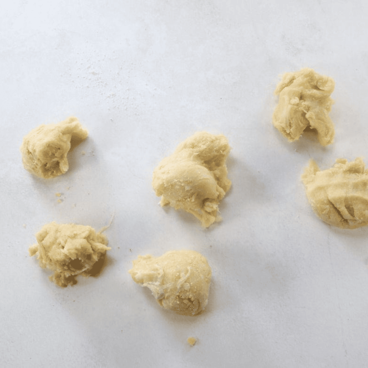 Adding almond flour, baking powder, egg, and apple cider vinegar to melted cheese to form fathead dough for keto bagels.