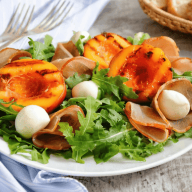 Air fryer grilled nectarines topped with whipped cream on a white plate