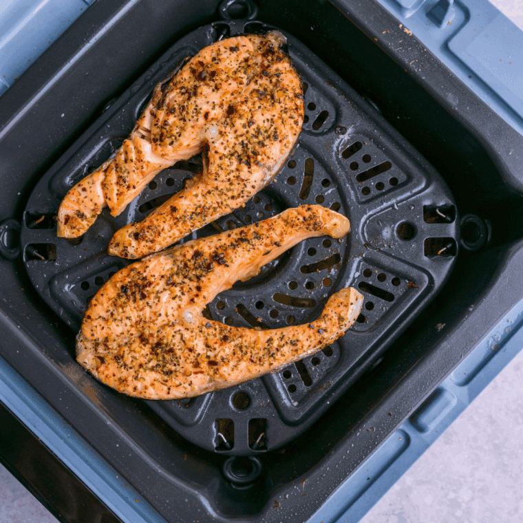 Cooked salmon steaks in the air fryer basket.