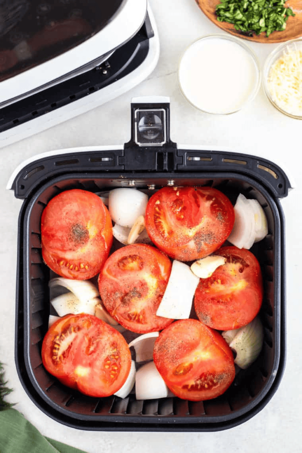 Placing tomatoes, jalapeños, onions, and garlic in the air fryer basket, cooking for 15-20 minutes until charred and roasted.