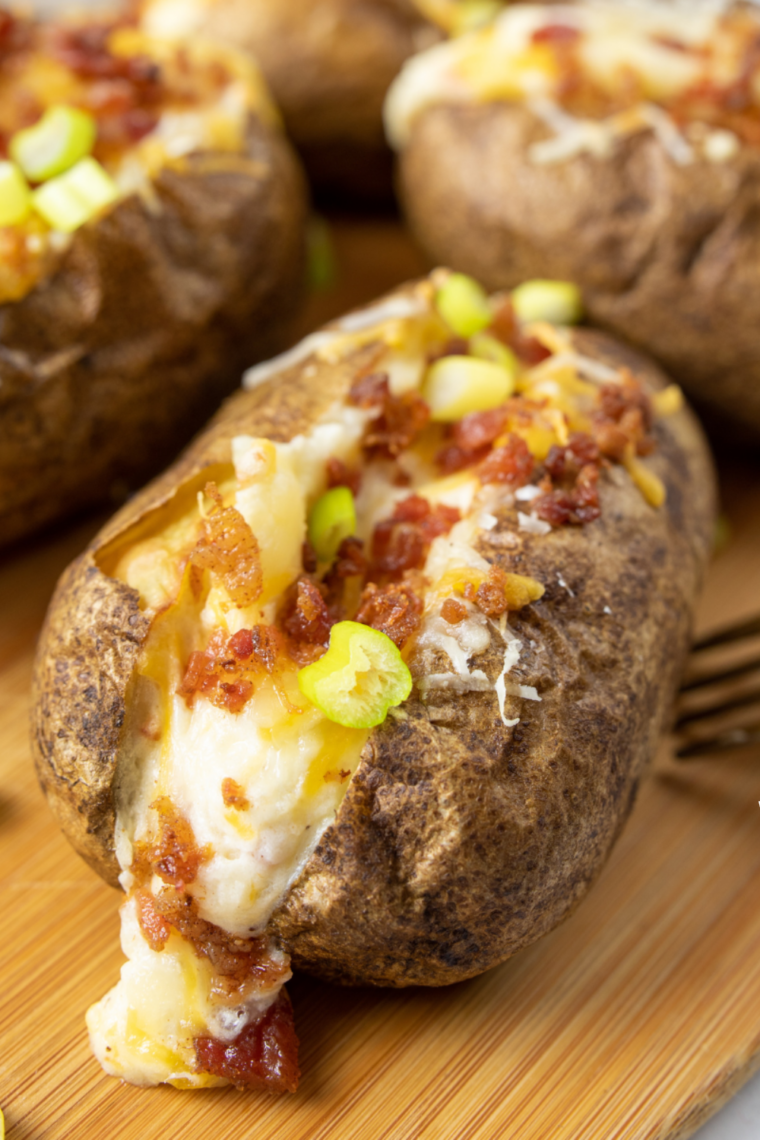 Air fryer twice baked potatoes in the air fryer basket with browned melted cheddar on top