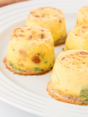 Air fryer veggie egg bites on a white plate, golden and fluffy with visible bell peppers and onions